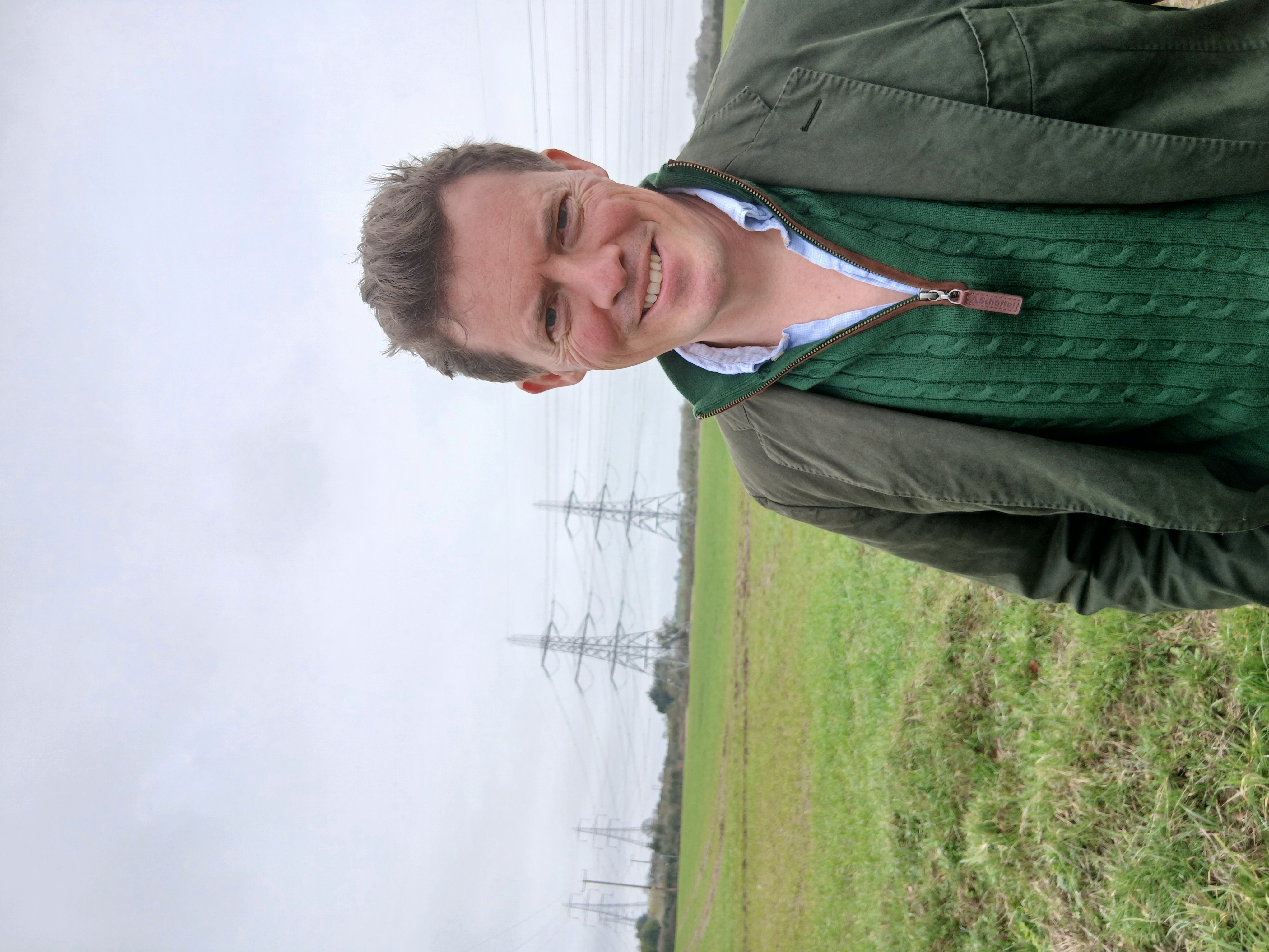 Tom Faulkner standing near pylons in the Suffolk countryside